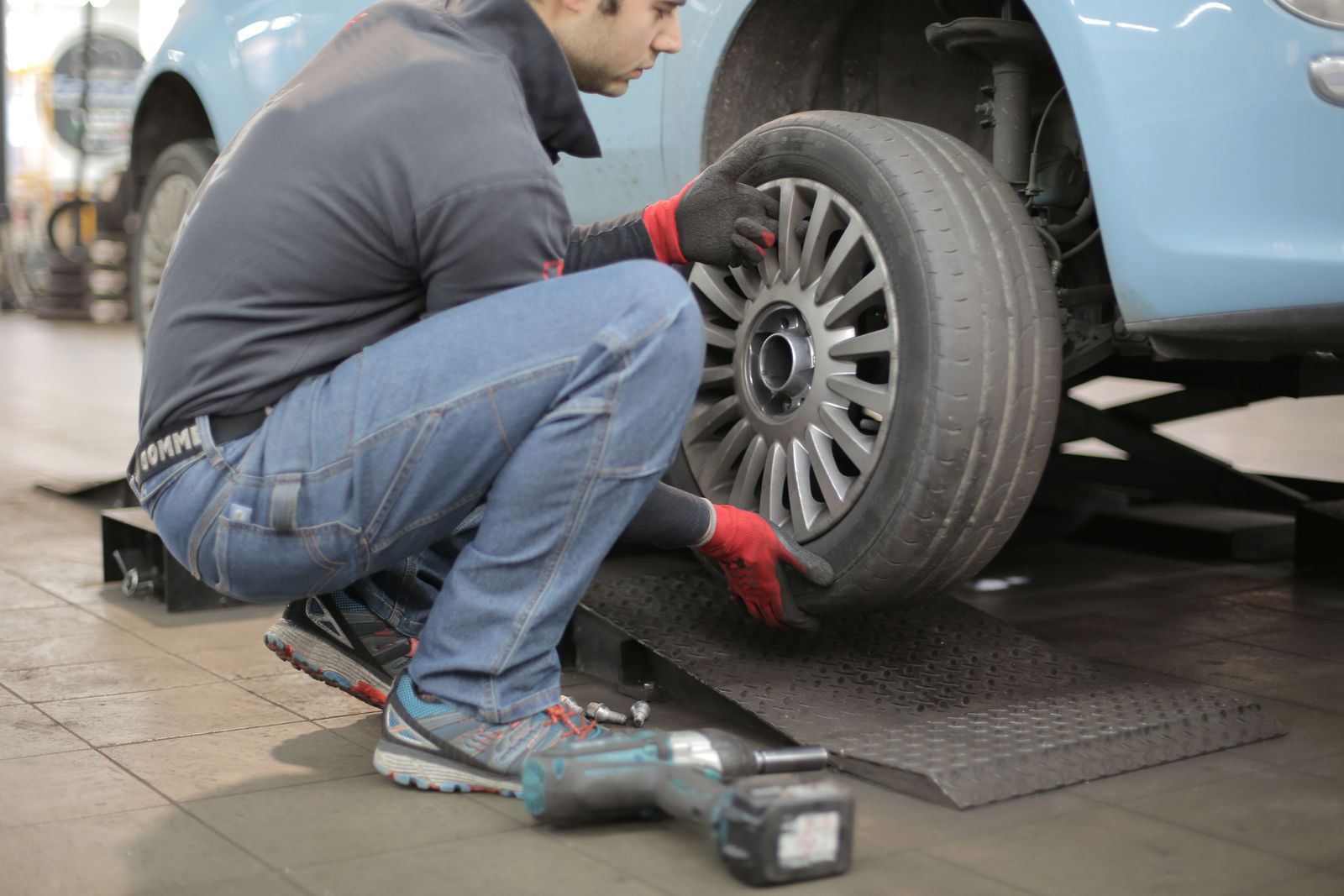 A technician fitting a replacement tire onto a car